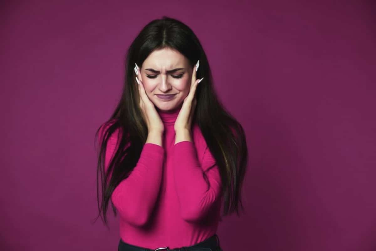 A girl with annoying tooth pain is holding head in hands